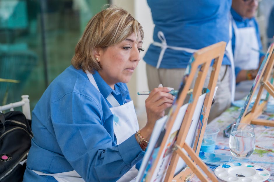 Focused woman painting at easel during an indoor art workshop, showcasing creativity and leisure.