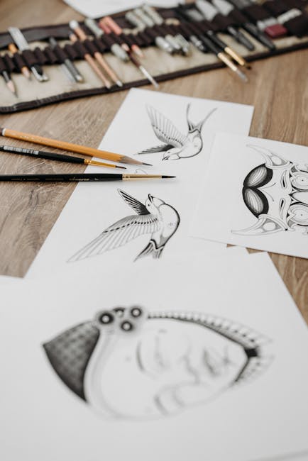 Detailed pencil sketches of tattoos with artistic designs on a wooden surface. Includes tools like paintbrushes and pencils.